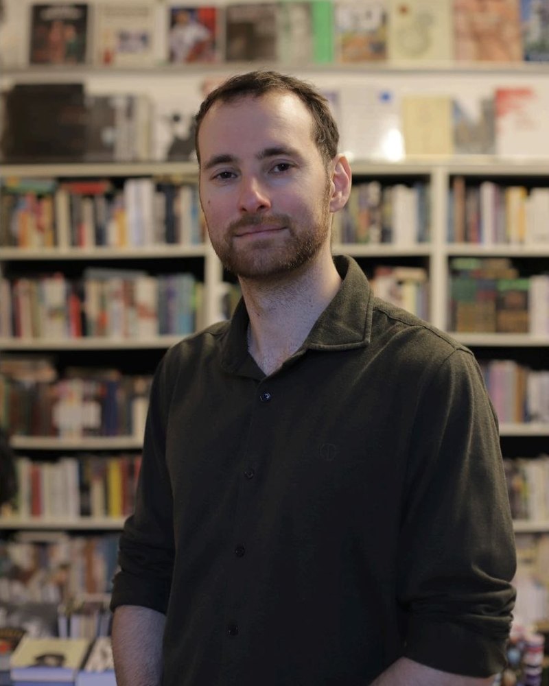 Робин Гомар, преподаватель французского, на фоне книжных полок